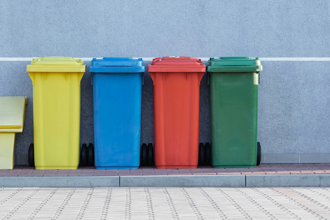 Four colour-coded wheelie bins lined up at the kerb for collection